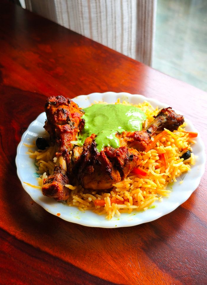 Home Delicious grilled chicken with flavorful rice and green sauce garnished on a white plate.