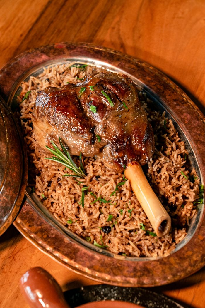 Savor a tasty lamb shank served on a plate of aromatic spiced rice.